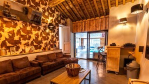 A cozy living area with a brown leather sofa, a wooden coffee table, and a patterned wall. - Villa in Coo With Indoor Pool & Near Waterfalls (Stavelot)