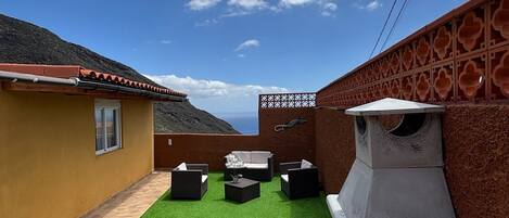 A backyard with artificial grass, outdoor furniture, a barbecue grill, and a decorative wall.