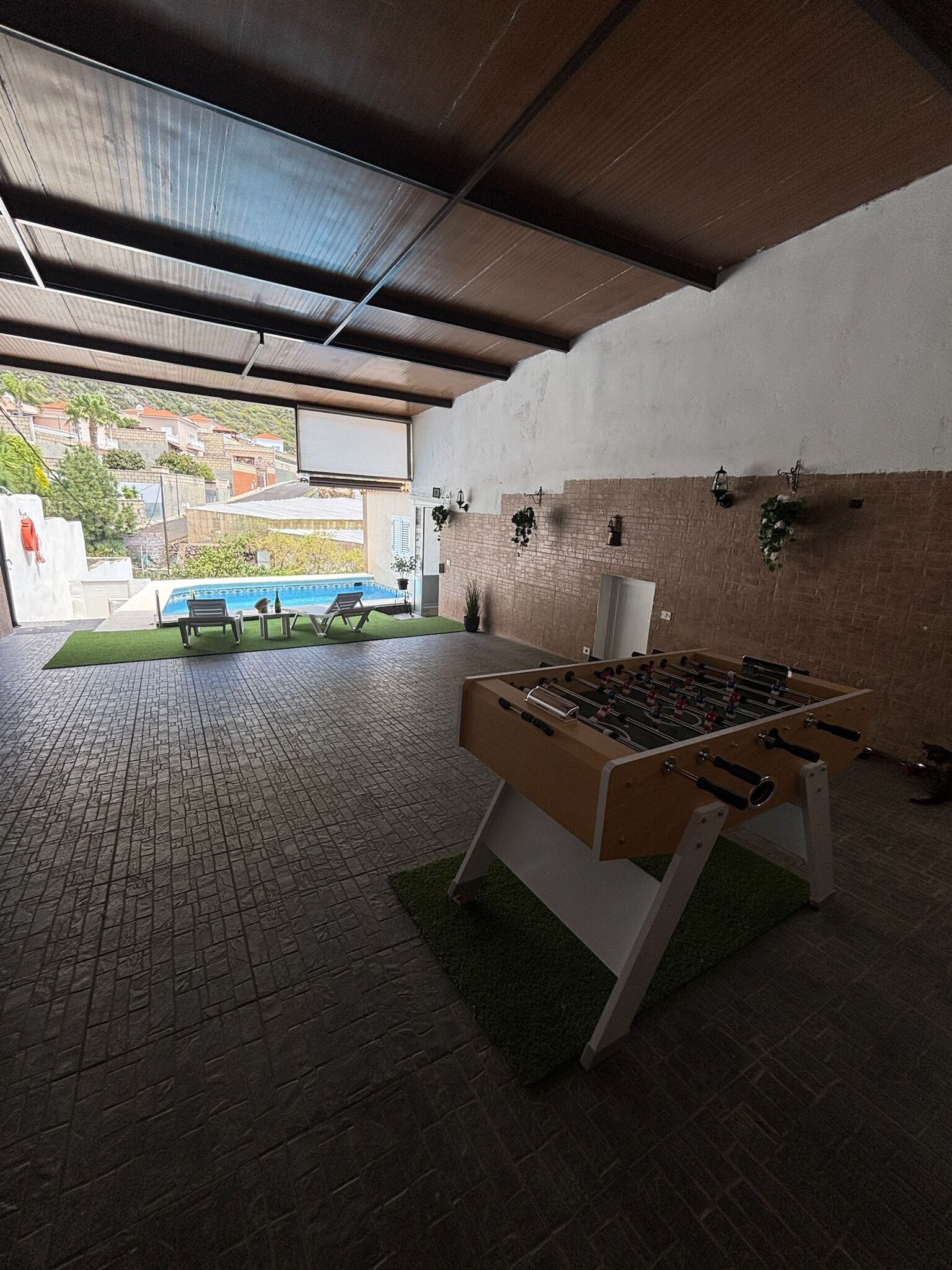 An indoor recreational area with a foosball table, a pool table, and a view of a residential neighborhood.