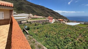 Une propriété située sur une colline, avec des vignes en terrasses, un mur de pierre et un bâtiment doté d’un toit rouge.
