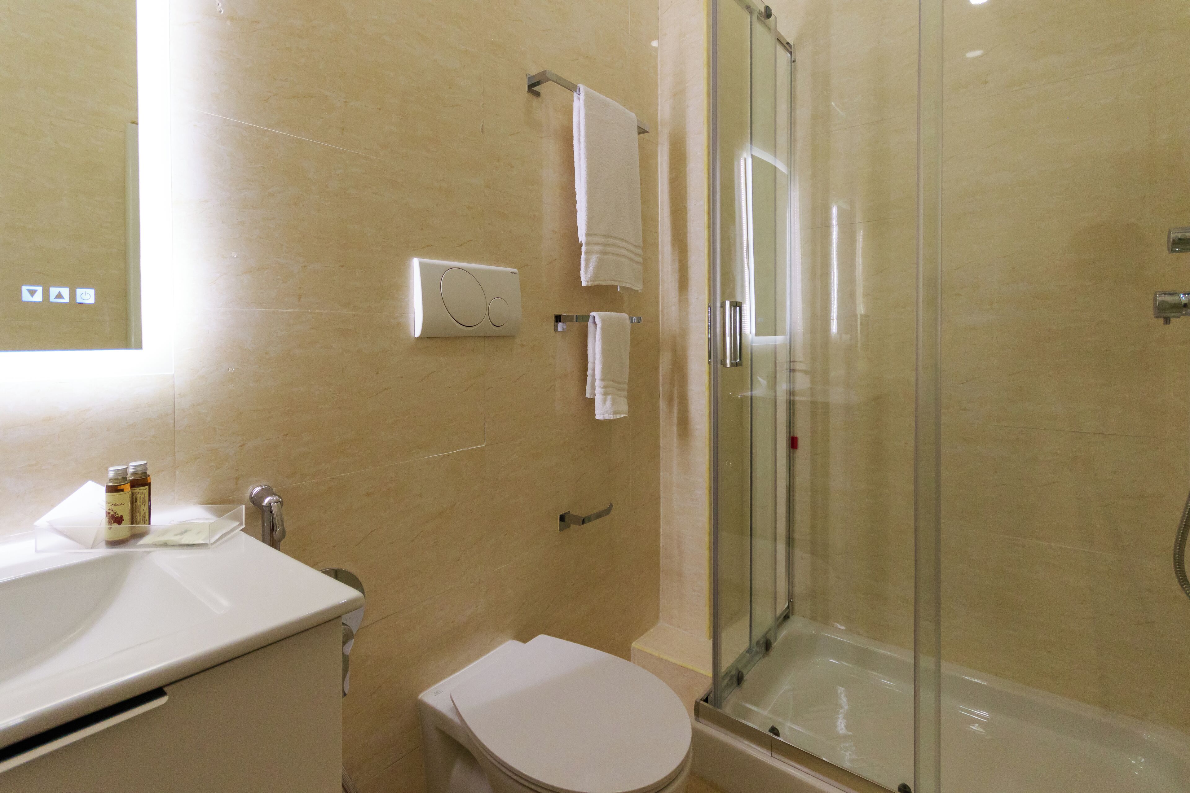 Een badkamer met een douchecabine van glas, een wit wastafel en een toilet.