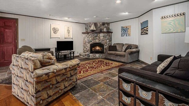 A cozy living room with a stone fireplace, a television, and a patterned rug.