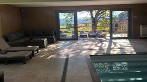 A spacious living area with a large sliding glass door leading to a patio with outdoor furniture and a view of a green landscape. - Farmhouse in Ardennes Near Coo Waterfalls (Trois-Ponts)