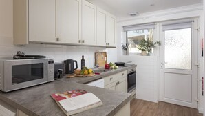 Une cuisine moderne avec des meubles blancs, un four à micro-ondes, un évier et une fenêtre donnant sur l’extérieur.