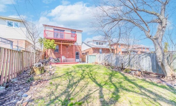 Stroll through the charming backyard, surrounded by lush greenery and a beautiful tree, with a cozy balcony overlooking the serene surroundings.
