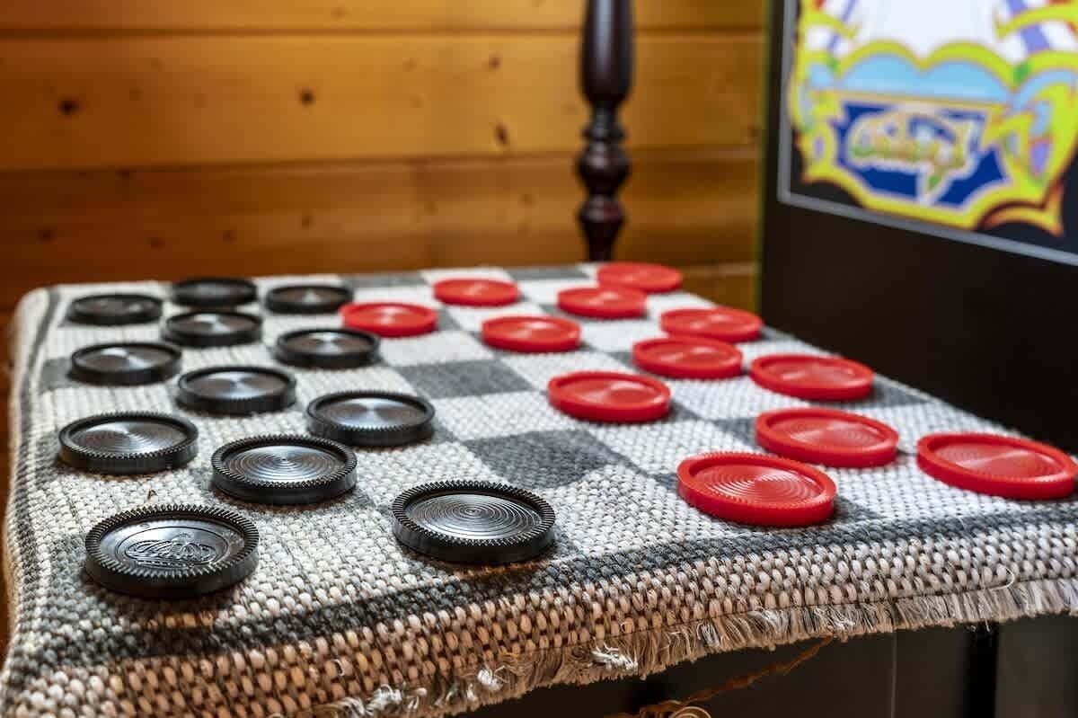 Un tablero de juego con cuadros, con piezas negras y rojas, sobre una superficie tejida.