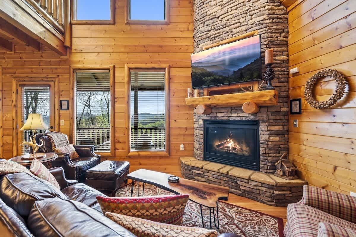 L’intérieur chaleureux d’un chalet avec une cheminée en pierre, des murs en bois et un coin salon confortable.