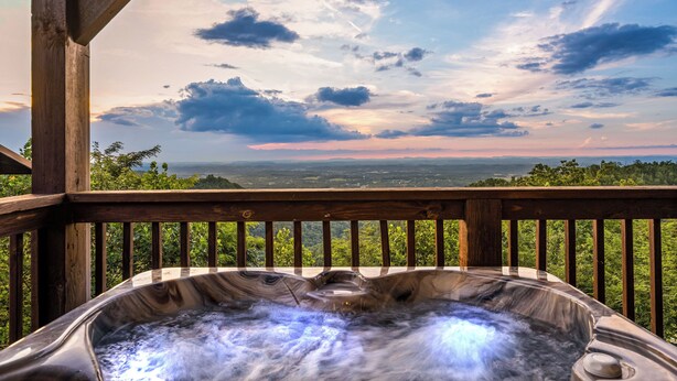 A hot tub on a wooden deck with a scenic view of a forest and mountains in the background. - Long range sunset views from Hot Tub, free attractions, Resort pool (Sevierville)