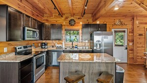 A modern kitchen with granite countertops, stainless steel appliances, and wooden cabinetry. - Long range sunset views from Hot Tub, free attractions, Resort pool (Sevierville)