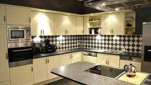 A modern kitchen with a microwave, oven, and stove, featuring a checkered backsplash and light-colored cabinets. - Villa in Vielsalm With Lake Views and Pool (Vielsalm)