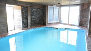 A swimming pool with stone walls and a glass door leading outside. - Villa in Vielsalm With Lake Views and Pool (Vielsalm)