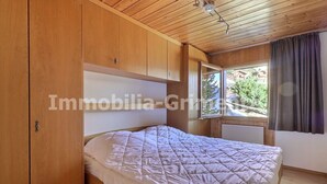 A bedroom with a bed, wooden ceiling, and a window with curtains.