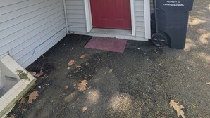 A house with a red door, a small window, and a black trash bin labeled 'PROPERTY OF Old Orchard Beach.'