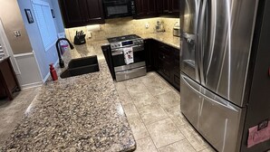 A modern kitchen with dark wood cabinets, stainless steel appliances, and a granite countertop. - Detached home with heated saltwater pool 45 minutes from Toronto (Whitby)