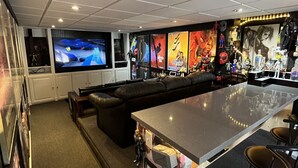 A modern bar area with a large TV, seating, and a bar counter. - Detached home with heated saltwater pool 45 minutes from Toronto (Whitby)