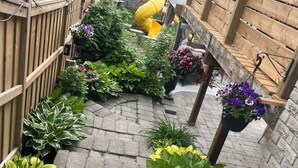 A garden pathway with a wooden fence, potted plants, and a yellow slide. - Detached home with heated saltwater pool 45 minutes from Toronto (Whitby)