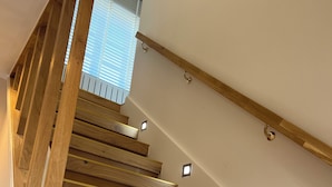 A wooden staircase with a handrail and small lights along the steps.