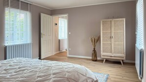 A bedroom with a bed, a wardrobe, a radiator, and a window with blinds.