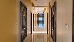 A long, narrow hallway with a polished floor, flanked by walls with decorative panels and recessed lighting. - Hotel The Siwan International (Siwan)