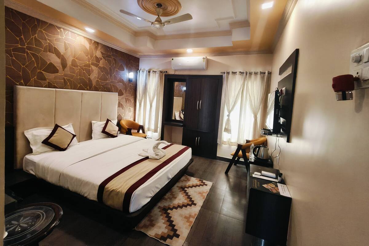 A hotel room with a large bed, a ceiling fan, a stone wall, and a desk with a mirror.