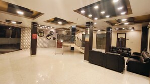 A hotel lobby with a reception desk, seating area, and a staircase leading to upper floors. - Hotel The Siwan International (Siwan)