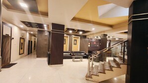 A spacious lobby with a staircase, a reception desk, and a seating area. - Hotel The Siwan International (Siwan)