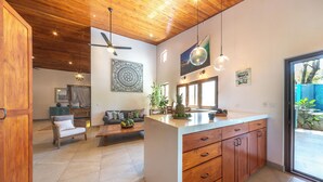 A modern kitchen with wooden cabinets, a central island, and pendant lighting.