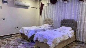 A bedroom with two beds, an air conditioning unit, and a patterned floor. - Hotel El Muhtar (Akcakale)