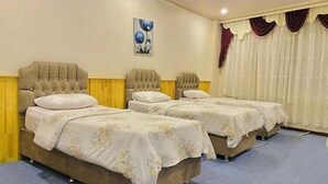 A hotel room with two beds, each with a tufted headboard, a painting on the wall, and curtains on the window. - Hotel El Muhtar (Akcakale)