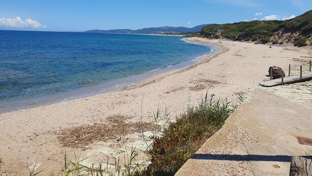 A beach with clear blue water, sandy shore, and a wooden walkway. - Bilocale Confort Viviana-LaCiaccia Style (La Ciaccia)