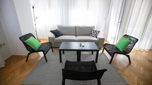Een woonkamer met een bank, twee fauteuils, een salontafel en een vloerlamp.