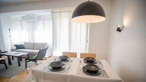 Een eetgedeelte met een tafel voor vier personen, een bank en een lamp in een moderne woonruimte.