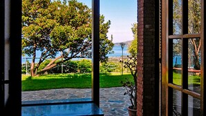 A view from a window of a building with a stone pathway leading to a grassy area and a tree. - Il Giardino dei Filosofi (Ascea)