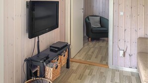 A room with a flat-screen TV mounted on the wall, a small table with a remote control, and a wicker basket. - Gorgeous home in Odder with WiFi (Odder)