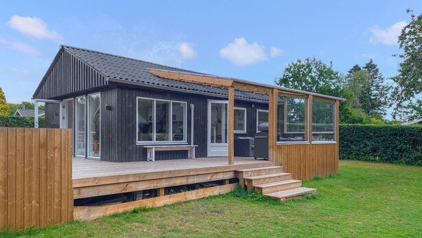 A modern, single-story house with a wooden deck, large windows, and a covered patio area. - Gorgeous home in Odder with WiFi (Odder)