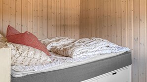 A bed with a white and floral patterned bedspread, a red and white striped pillow, and a grey storage compartment below. - Gorgeous home in Odder with WiFi (Odder)