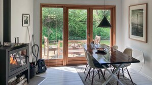 A dining area with a table, chairs, a hanging light fixture, and a view of a garden through large glass doors. - 2 bedroom beautiful home in Jægerspris (Jægerspris)