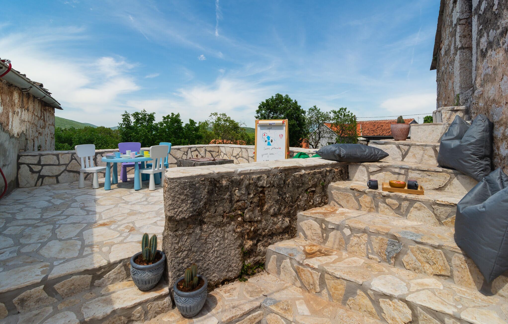 A stone patio with outdoor seating, a whiteboard with a drawing, and potted cacti.