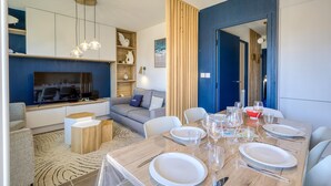 A modern living room with a TV, sofa, and dining area set up for a meal. - Awesome home in Dolus-d'Oléron with sauna (Dolus-d'Oléron)
