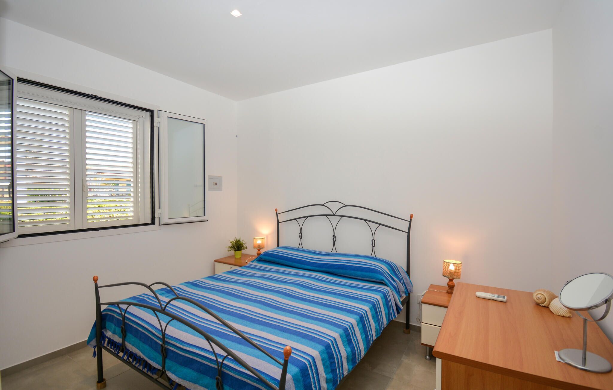 Ein Schlafzimmer mit Bett, Nachttischen, Schreibtisch, Stuhl und Spiegel.