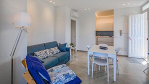 Ein modernes Wohnzimmer mit einer Couch, einem Esstisch und einer Küche im Hintergrund.