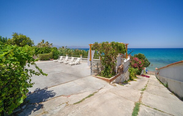 Terraço no telhado com espreguiçadeiras, pérgola coberta por plantas trepadeiras e vista para o mar.