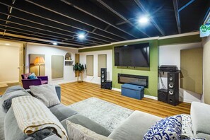 A modern living room with a sofa, a coffee table, a TV, and a sound system. - 6 Mi to Summerfest Park: Home w/ Game Room! (Cudahy)