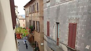 A narrow street with buildings on either side, featuring balconies and potted plants. - Casa Gioia - Casa Olivieri  (Pienza)