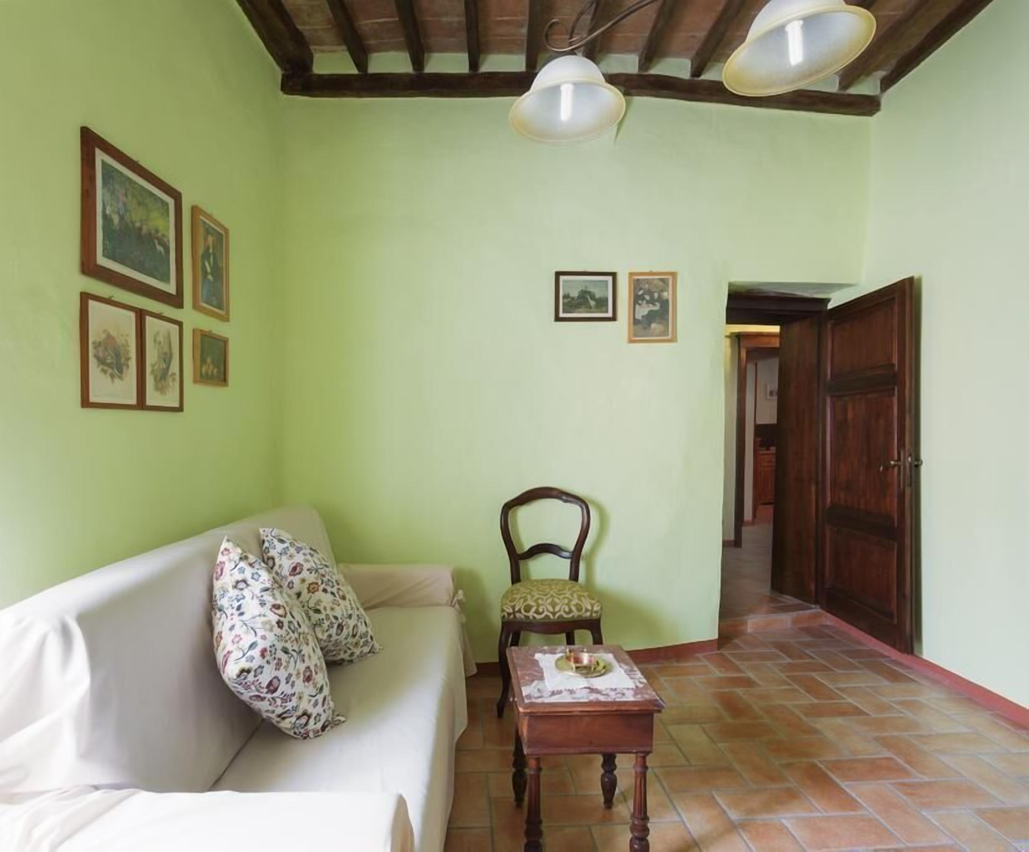 Un salon comprenant un canapé, une chaise en bois, une petite table et une porte donnant sur une autre pièce.