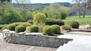 A landscaped garden with neatly trimmed hedges and a stone retaining wall. - Farmhouse in Belgium Near Lake Coo & Jacuzzi (Trois-Ponts)