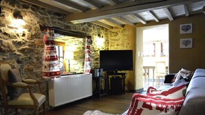 A cozy living room with a stone wall, a fireplace, a television, and a comfortable seating area. - Farmhouse in Belgium Near Lake Coo & Jacuzzi (Trois-Ponts)