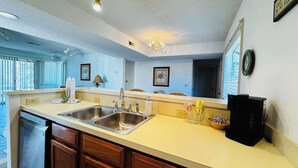 A kitchen with a double sink, wooden cabinets, a dishwasher, and a black appliance on the counter. - Bay Tree cozy 2BR condo on the ground floor (Little River)