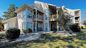 A multi-story apartment building with balconies, a covered outdoor seating area, and a well-maintained lawn. - Bay Tree cozy 2BR condo on the ground floor (Little River)
