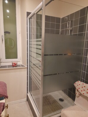 Een douche, handdoeken, zeep, toiletpapier